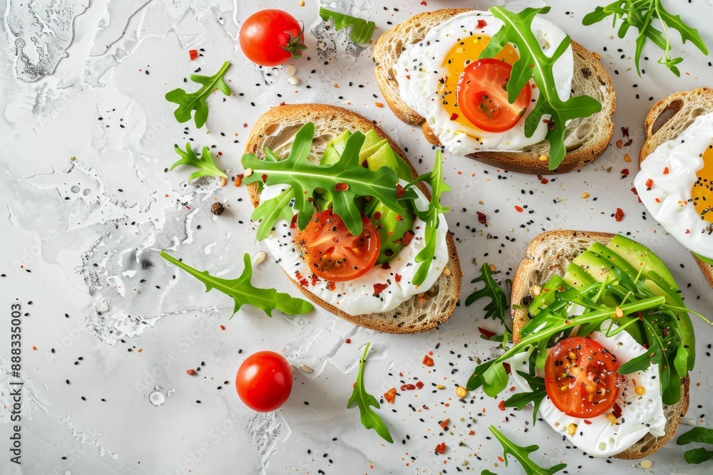 Healthy and tasty wholegrain breakfast sandwich with avocado egg and arugula salad on light background viewed from the top Healthy and tasty wholegrain breakfast sandwich with avocado egg and arugula salad on light background viewed from the top