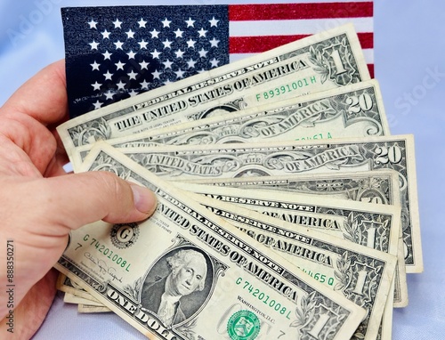 Notas de dolares em diversos valores com fundo branco e bandeira dos Estados Unidos da America.