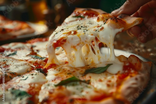 One hand holding a slice of freshly baked Pizza Margherita on a white plate.