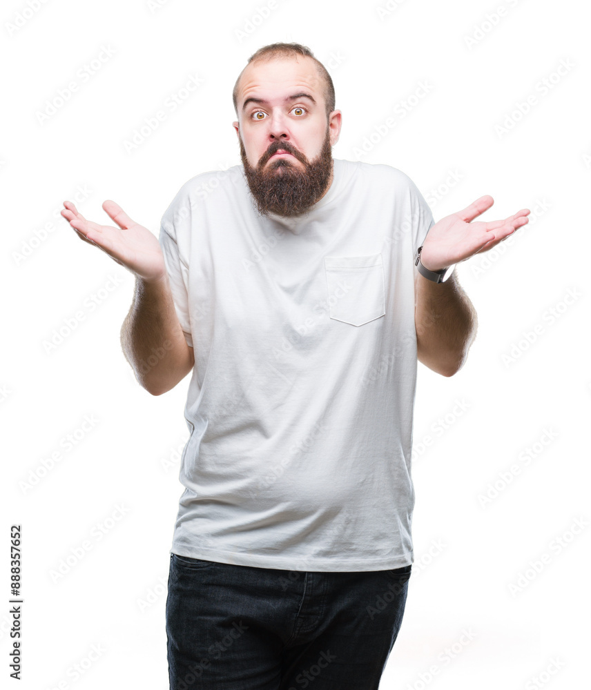 Young caucasian hipster man wearing casual t-shirt over isolated background clueless and confused expression with arms and hands raised. Doubt concept. Young caucasian hipster man wearing casual t-shirt over isolated background clueless and confused expression with arms and hands raised. Doubt concept.