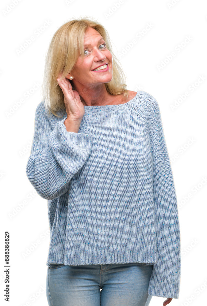 Middle age blonde woman wearing winter sweater over isolated background smiling with hand over ear listening an hearing to rumor or gossip. Deafness concept. Middle age blonde woman wearing winter sweater over isolated background smiling with hand over ear listening an hearing to rumor or gossip. Deafness concept.