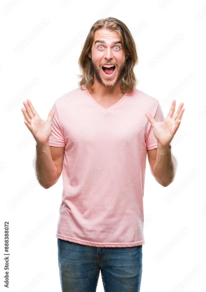 Young handsome man with long hair over isolated background celebrating crazy and amazed for success with arms raised and open eyes screaming excited. Winner concept