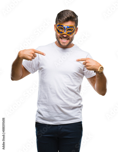 Young handsome man wearing carnival mask over isolated background looking confident with smile on face, pointing oneself with fingers proud and happy.