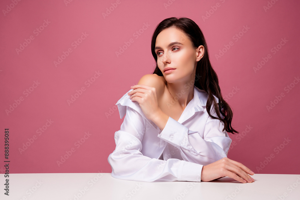 Photo of brunette hair feminine girl sit table touch white soft shirt isolated pastel color background Photo of brunette hair feminine girl sit table touch white soft shirt isolated pastel color background