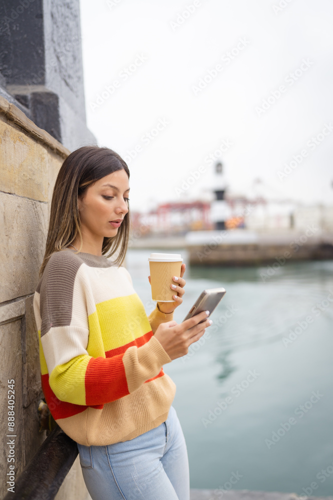 Young woman using smartphone and drinking coffee at port of callao Young woman using smartphone and drinking coffee at port of callao