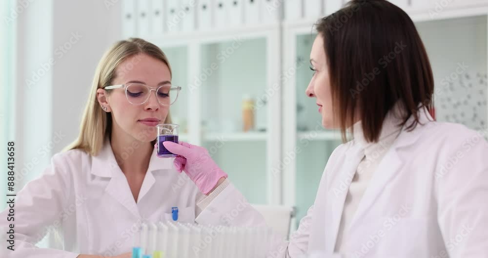 Laboratory worker offers colleague to test aroma of liquid Laboratory worker offers colleague to test aroma of liquid