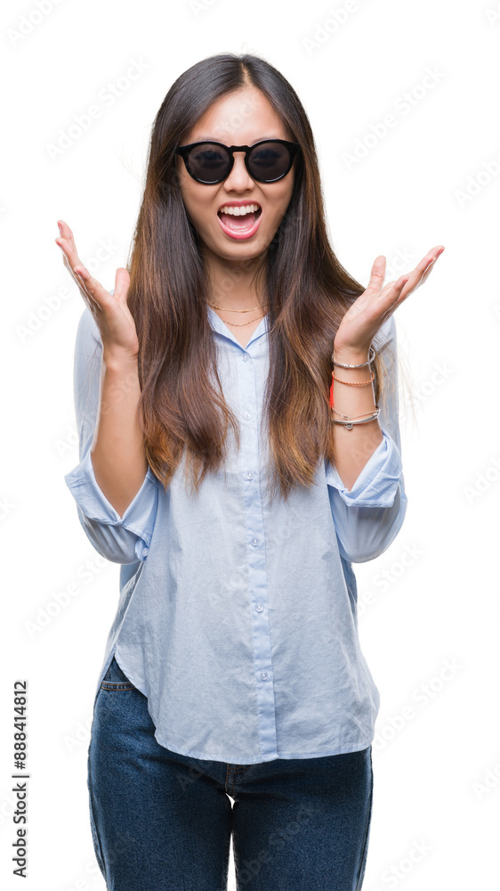 Young asian woman wearing sunglasses over isolated background celebrating mad and crazy for success with arms raised and closed eyes screaming excited. Winner concept Young asian woman wearing sunglasses over isolated background celebrating mad and crazy for success with arms raised and closed eyes screaming excited. Winner concept