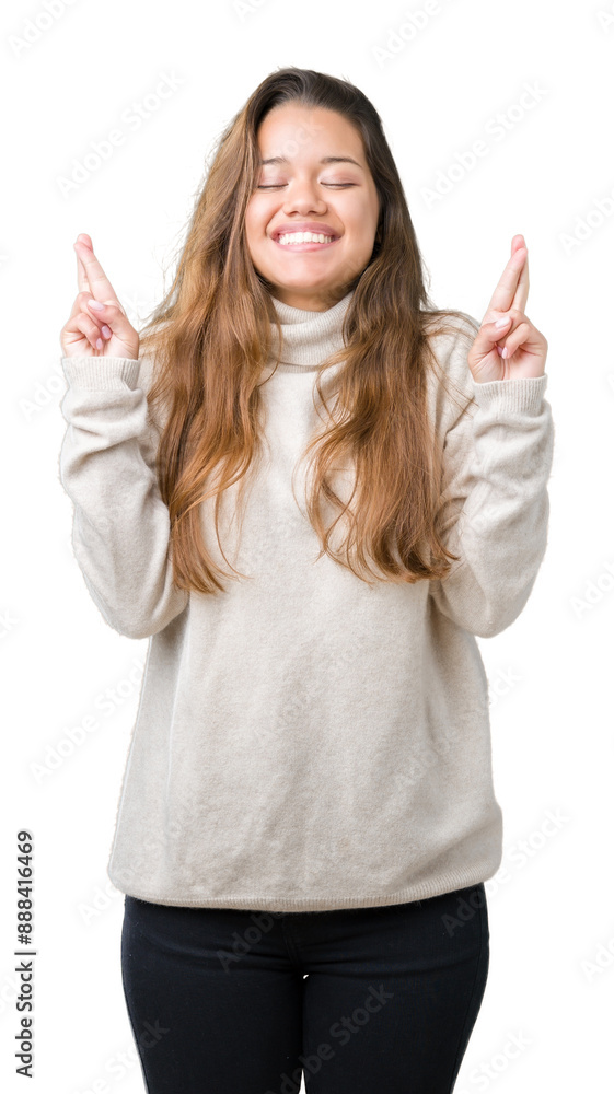 Young beautiful brunette woman wearing turtleneck sweater over isolated background smiling crossing fingers with hope and eyes closed. Luck and superstitious concept. Young beautiful brunette woman wearing turtleneck sweater over isolated background smiling crossing fingers with hope and eyes closed. Luck and superstitious concept.
