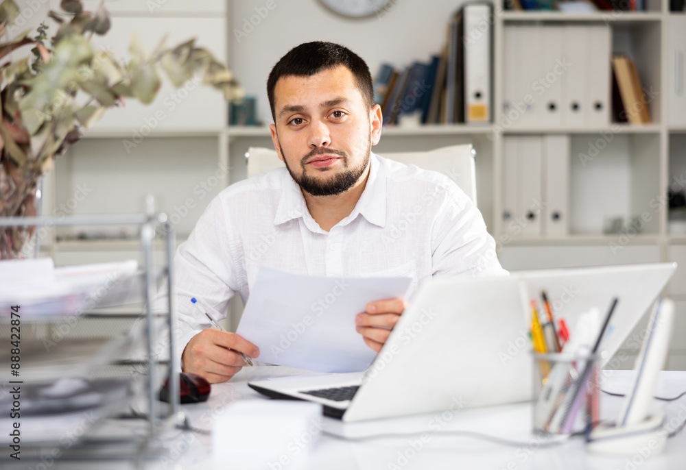 Fototapeta premium Caucaisan businessman doing his daily work in office. Cheerful man sitting at desk and working.