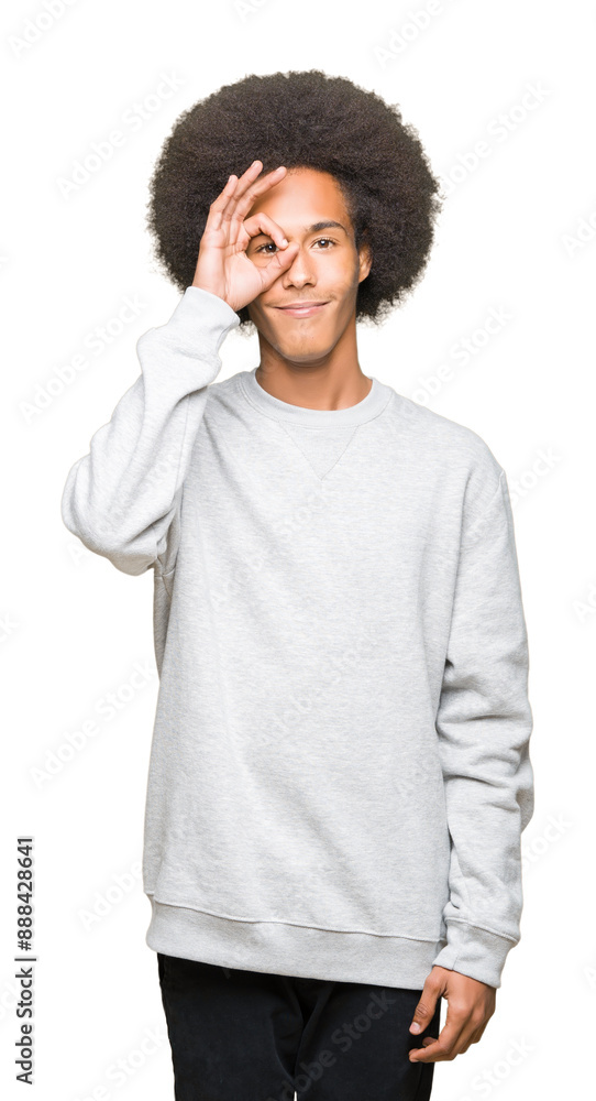 Young african american man with afro hair wearing sporty sweatshirt doing ok gesture with hand smiling, eye looking through fingers with happy face. Young african american man with afro hair wearing sporty sweatshirt doing ok gesture with hand smiling, eye looking through fingers with happy face.