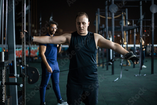 Man Doing Cable Fly Exercise In Modern Gym At Night photo