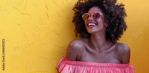 Woman With Curly Hair Laughing In Sunglasses Against Yellow Wall