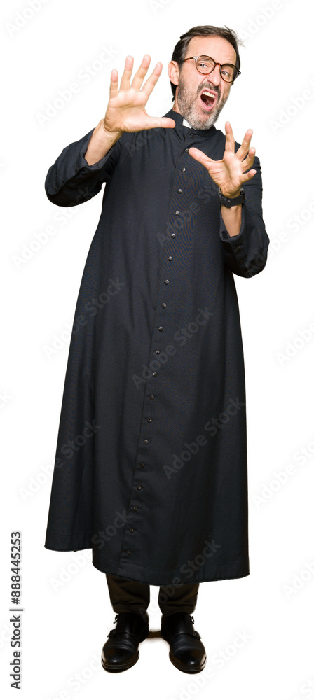 Middle age priest man wearing catholic robe afraid and terrified with fear expression stop gesture with hands, shouting in shock. Panic concept. Middle age priest man wearing catholic robe afraid and terrified with fear expression stop gesture with hands, shouting in shock. Panic concept.