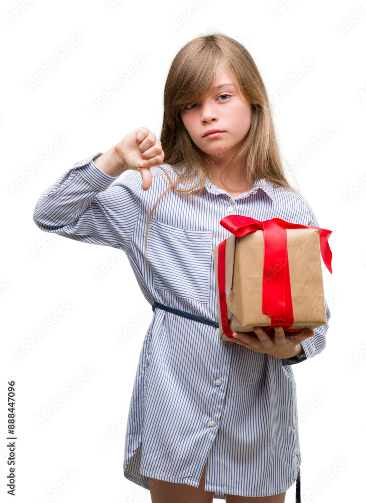Young blonde toddler holding a present with angry face, negative sign showing dislike with thumbs down, rejection concept Young blonde toddler holding a present with angry face, negative sign showing dislike with thumbs down, rejection concept