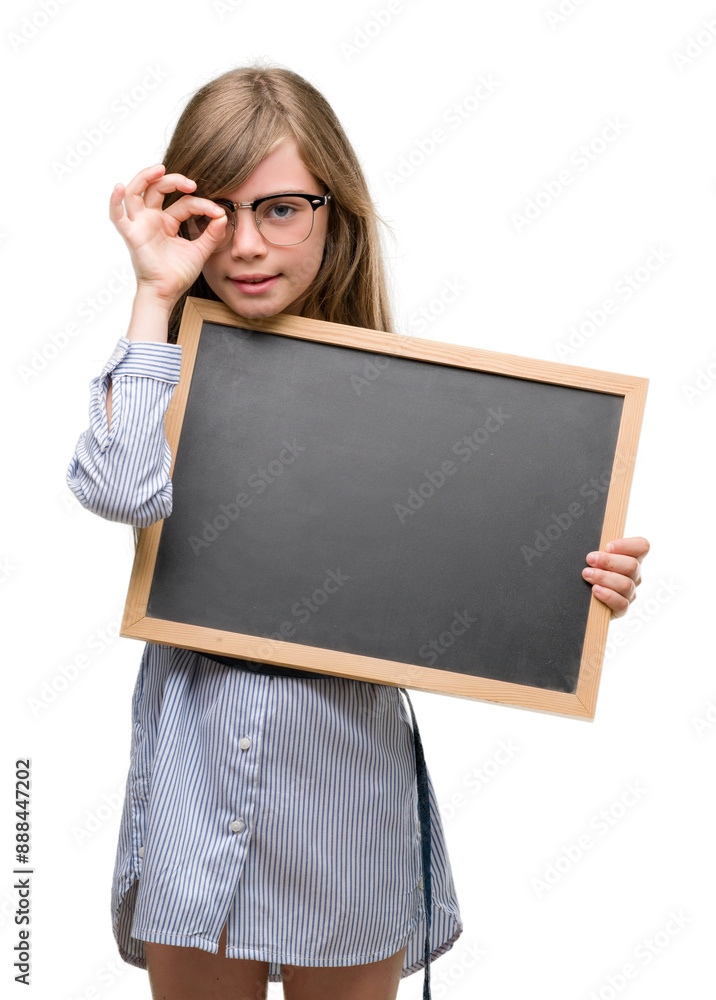 Young blonde child holding blackboard with happy face smiling doing ok sign with hand on eye looking through fingers Young blonde child holding blackboard with happy face smiling doing ok sign with hand on eye looking through fingers
