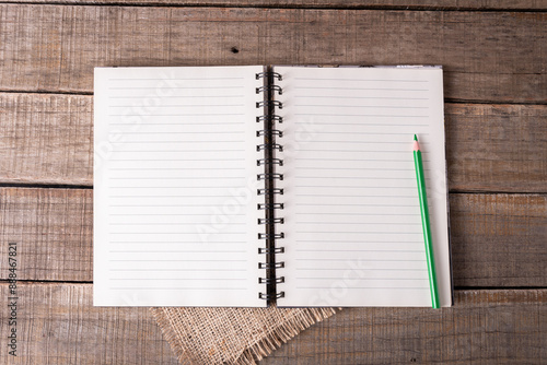 Spiral notebook with lined pages available and a green pencil on rustic wood.