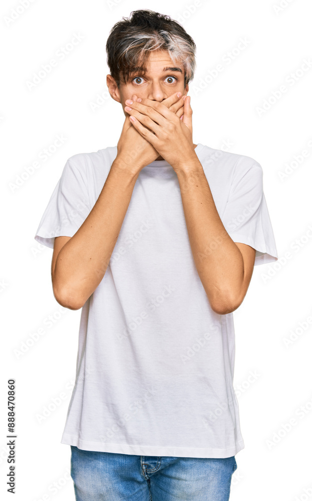 Young hispanic man wearing casual white tshirt shocked covering mouth with hands for mistake. secret concept. Young hispanic man wearing casual white tshirt shocked covering mouth with hands for mistake. secret concept.