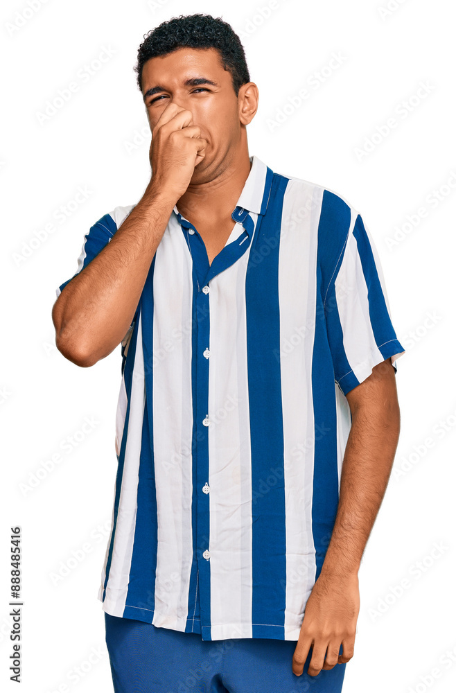 Young arab man wearing casual clothes smelling something stinky and disgusting, intolerable smell, holding breath with fingers on nose. bad smell Young arab man wearing casual clothes smelling something stinky and disgusting, intolerable smell, holding breath with fingers on nose. bad smell