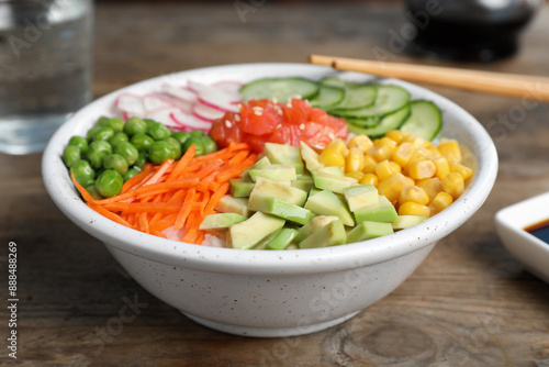 Delicious salad with salmon and vegetables on wooden table, closeup