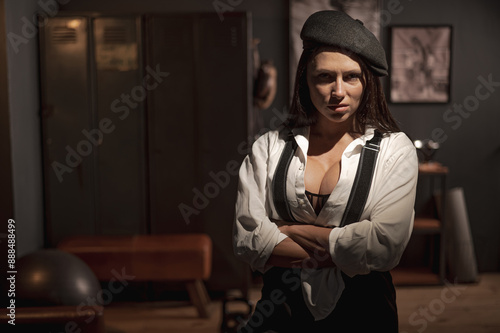 Caucasian woman in a Peaky Blinders style men's suit posing in a retro gym.