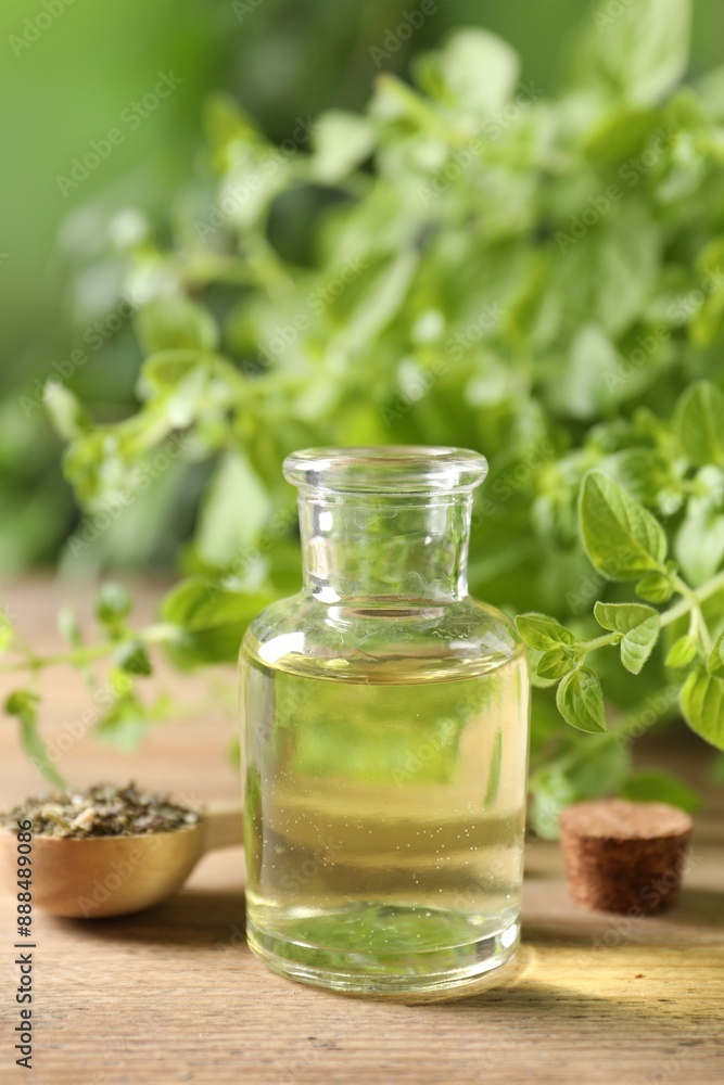 Essential oil in bottle, spoon with dry herb and oregano twigs on wooden table, closeup Essential oil in bottle, spoon with dry herb and oregano twigs on wooden table, closeup