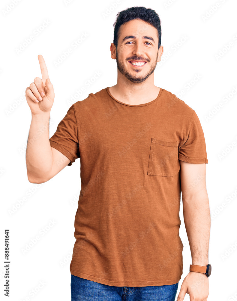 Young hispanic man wearing casual clothes showing and pointing up with finger number one while smiling confident and happy. Young hispanic man wearing casual clothes showing and pointing up with finger number one while smiling confident and happy.