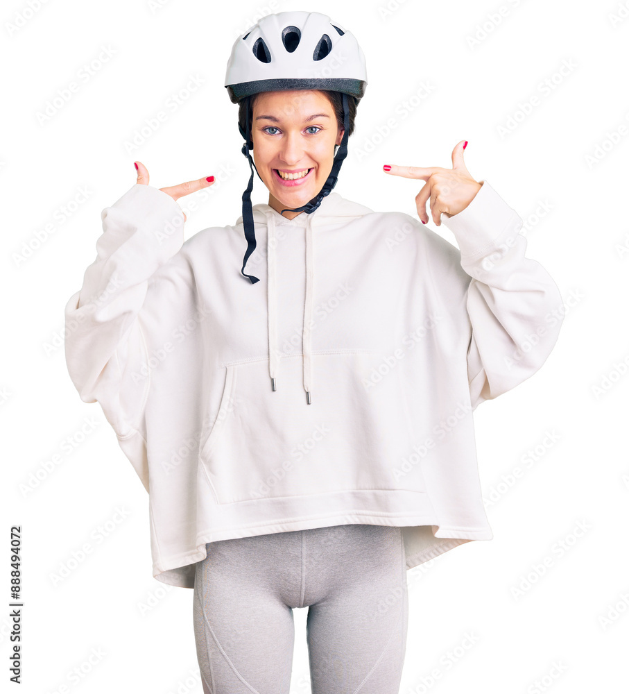 Beautiful brunette young woman wearing bike helmet and sporty clothes smiling cheerful showing and pointing with fingers teeth and mouth. dental health concept. Beautiful brunette young woman wearing bike helmet and sporty clothes smiling cheerful showing and pointing with fingers teeth and mouth. dental health concept.