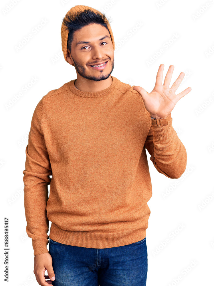 Handsome latin american young man wearing winter sweater and wool hat showing and pointing up with fingers number five while smiling confident and happy. Handsome latin american young man wearing winter sweater and wool hat showing and pointing up with fingers number five while smiling confident and happy.