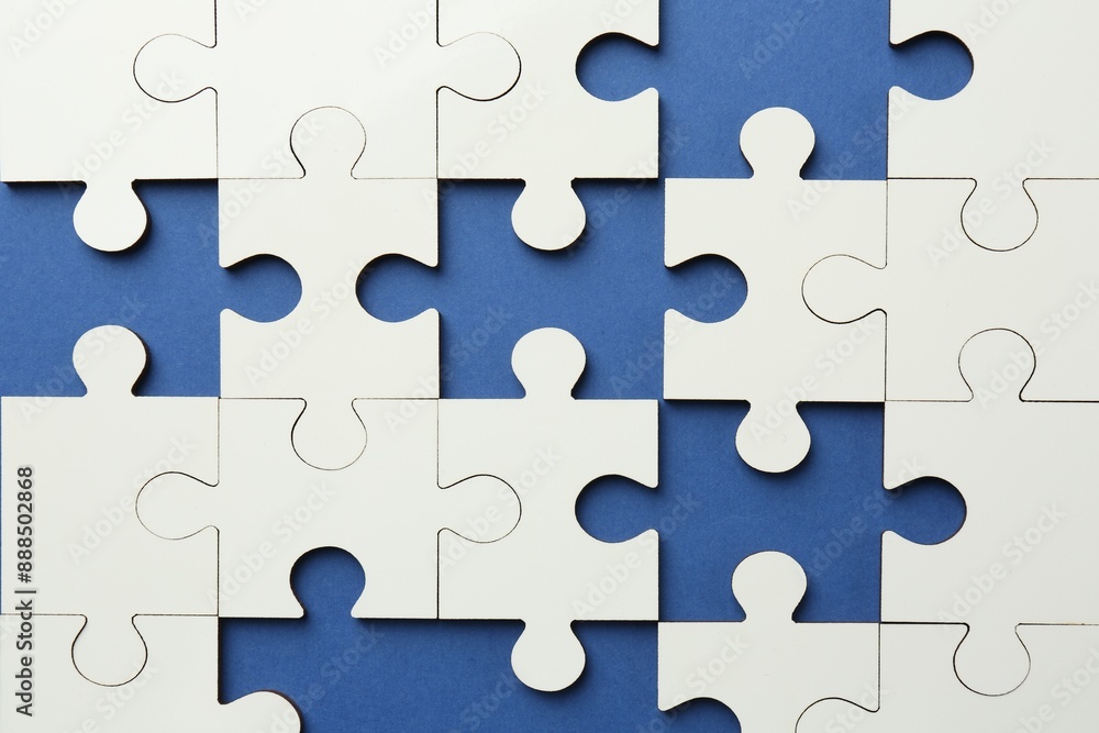 White puzzle with missing pieces on blue background, top view White puzzle with missing pieces on blue background, top view