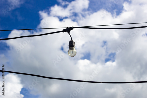 light bulb in blue sky with white clouds