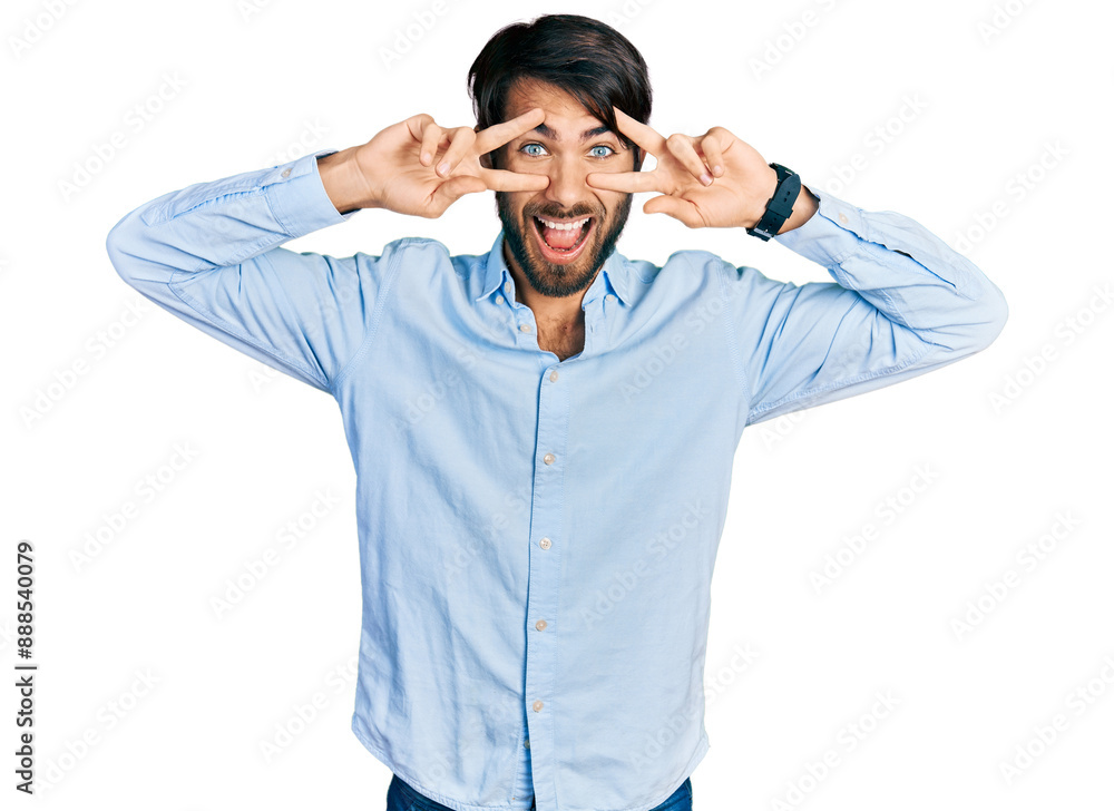 Hispanic man with blue eyes wearing business shirt doing peace symbol with fingers over face, smiling cheerful showing victory Hispanic man with blue eyes wearing business shirt doing peace symbol with fingers over face, smiling cheerful showing victory