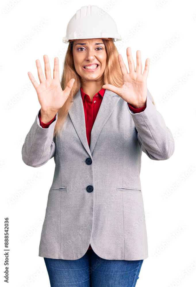 Beautiful young woman wearing architect hardhat afraid and terrified with fear expression stop gesture with hands, shouting in shock. panic concept. Beautiful young woman wearing architect hardhat afraid and terrified with fear expression stop gesture with hands, shouting in shock. panic concept.