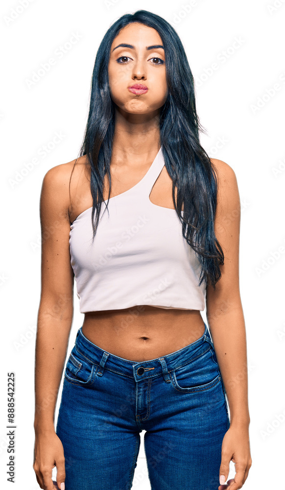 Beautiful hispanic woman wearing casual clothes puffing cheeks with funny face. mouth inflated with air, crazy expression. Beautiful hispanic woman wearing casual clothes puffing cheeks with funny face. mouth inflated with air, crazy expression.
