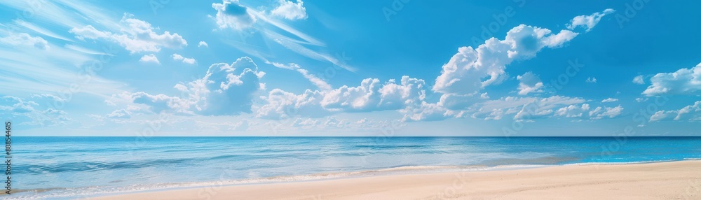Fototapeta premium Tranquil beach with calm ocean waves under clear blue sky and fluffy white clouds. Perfect relaxing getaway or summer destination.