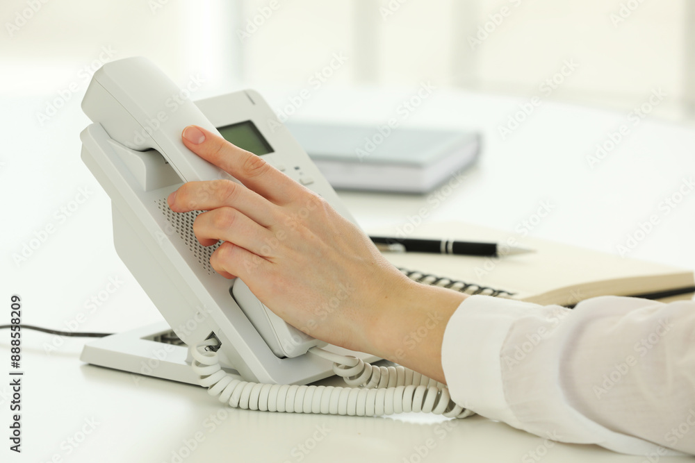 Assistant taking telephone handset at white table, closeup Assistant taking telephone handset at white table, closeup