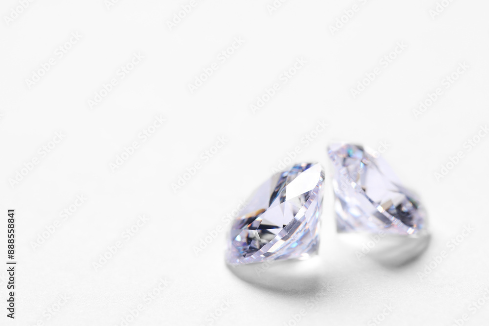 Two beautiful shiny diamonds on white background, closeup. Space for text Two beautiful shiny diamonds on white background, closeup. Space for text