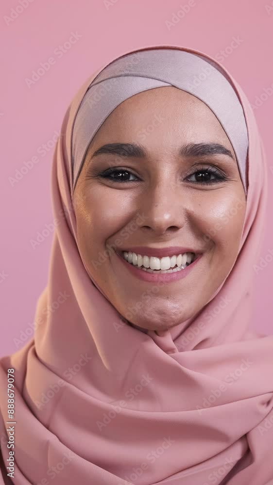 Vertical video. Happy muslim woman. Positive attitude. Traditional outfit. Portrait of joyful smiling female face in hijab isolated on pink studio background. Vertical video. Happy muslim woman. Positive attitude. Traditional outfit. Portrait of joyful smiling female face in hijab isolated on pink studio background.