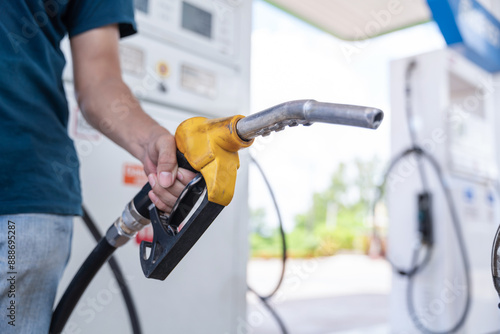 Valokuva Close up hand of A male holding a fuel nozzle against with gas station blurred background
