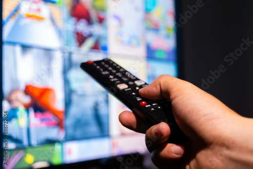 His hand was holding a remote control. Multimedia TV broadcasting online for entertainment to watch at his home. Background Broadcast concept.	 photo