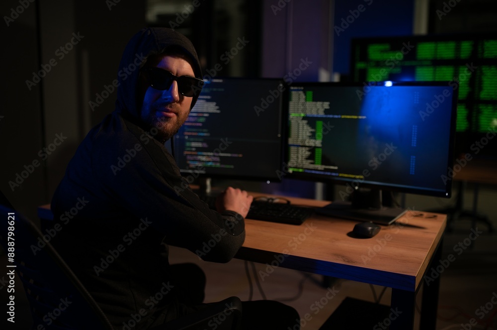 hacker sitting at desk in dark atmosphere. A computer programmer or hacker. Anonymous computer hacker. hacker sitting at desk in dark atmosphere. A computer programmer or hacker. Anonymous computer hacker.