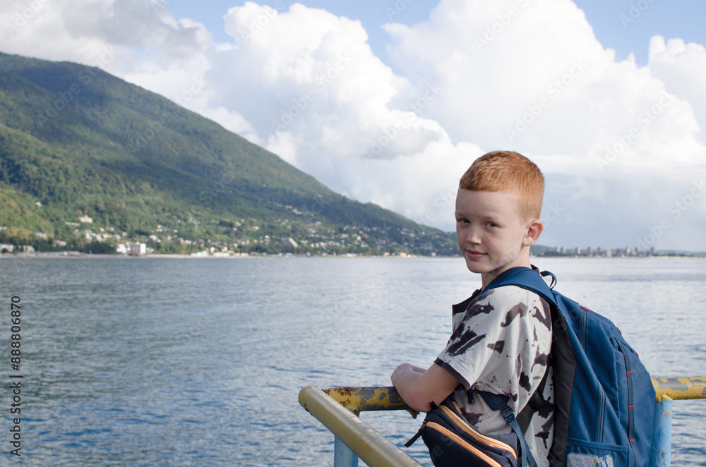 Boy on the pier with a backpack and a phone in his hands Boy on the pier with a backpack and a phone in his hands