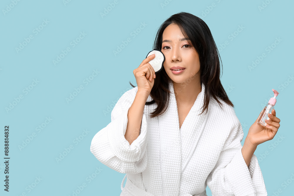 Young Asian woman with reusable cotton pad and cleanser on blue background