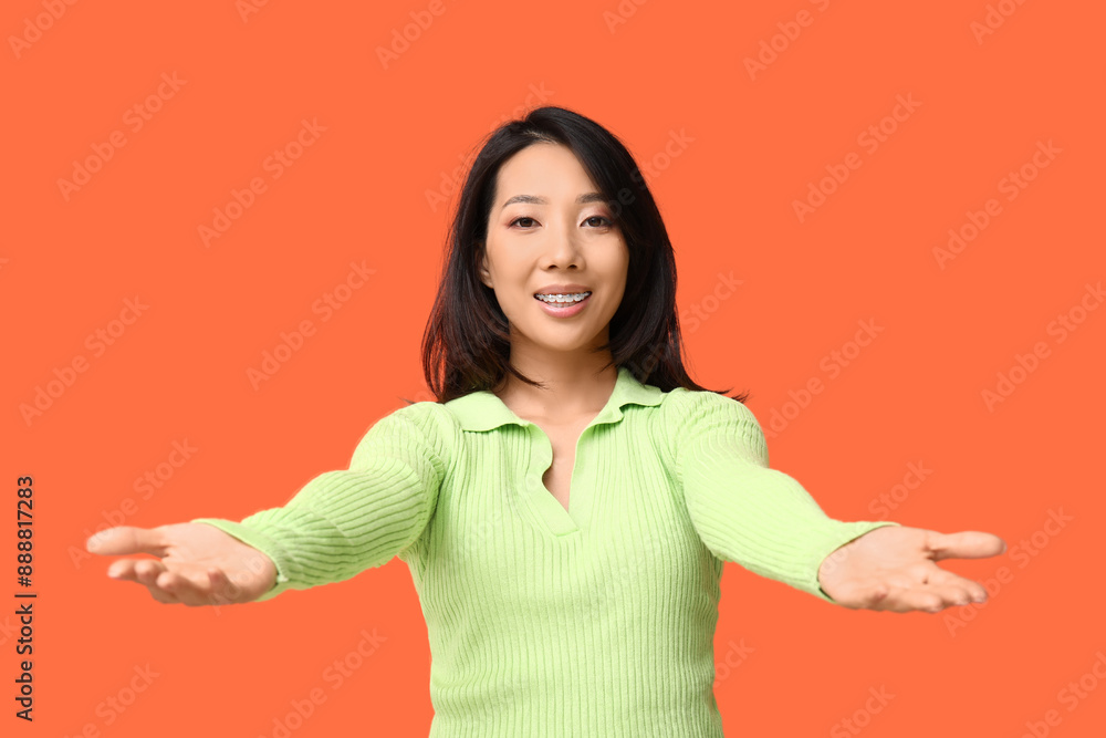 Young Asian woman opening arms for hug on orange background Young Asian woman opening arms for hug on orange background
