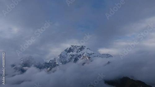 Aerial footage that is panning down of Nevado Auzangate, a mountain in Peru covered in ice and clouds and snow. photo