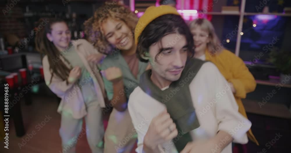 Group of joyful young people friends dancing looking at camera and laughing enjoying party in evening at home. Modern lifestyle and night life concept. Group of joyful young people friends dancing looking at camera and laughing enjoying party in evening at home. Modern lifestyle and night life concept.
