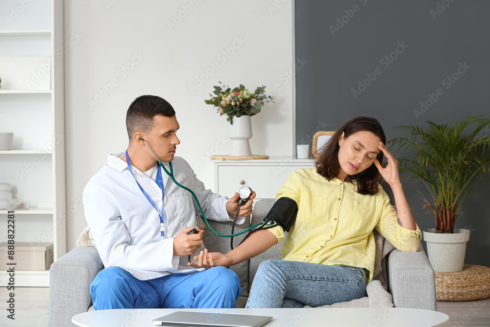 Male doctor measuring young woman's blood pressure at home Male doctor measuring young woman's blood pressure at home