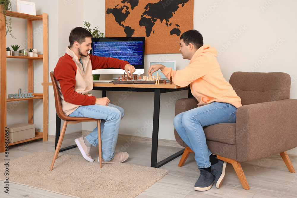 Fototapeta premium Handsome young brothers playing chess in room