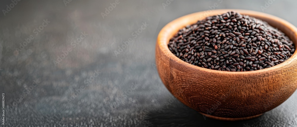 A wooden bowl, filled with black seeds, sits atop a black countertop Adjacent to it rests another identical wooden bowl, also brimming with black seeds A wooden bowl, filled with black seeds, sits atop a black countertop Adjacent to it rests another identical wooden bowl, also brimming with black seeds
