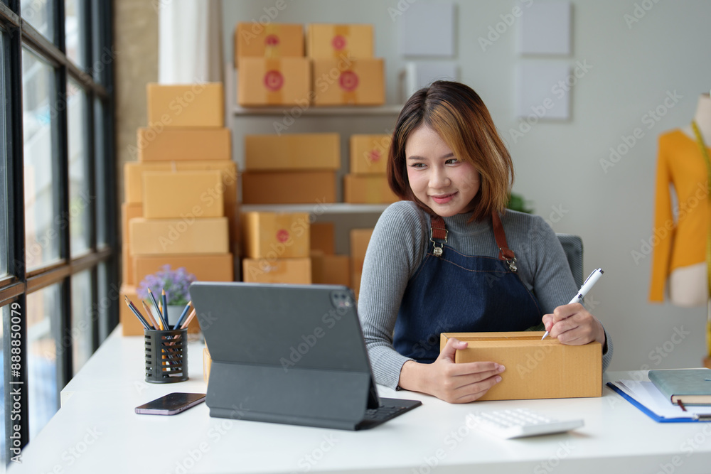 SME entrepreneurs, small female business entrepreneurs online selling ideas Asian business owner working on computer, recording information, delivery address, SME parcel box delivered to customer. SME entrepreneurs, small female business entrepreneurs online selling ideas Asian business owner working on computer, recording information, delivery address, SME parcel box delivered to customer.