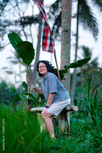 Woman enjoying the breezy afternoon sitting on a bamboo bench in the rice field photo